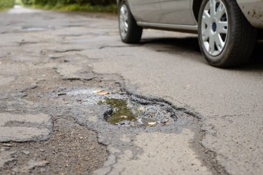 Modern gümüş araba bir sürü çukur ile yol boyunca ilerliyor.