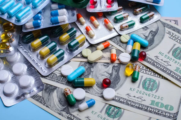 Cost of treatment, medicine, happy life without diseases concept. different pills lay on dollar bills symbolising high price on medicine