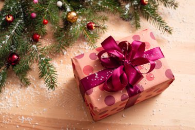 Menekşe ambalaj kağıdı ve kurdele hediye kutusunda. Noel süsü, köknar ağacı dalları, kar, ahşap masada takılar..