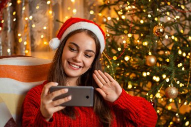 Noel Baba şapkalı mutlu kız, Covid-19 salgını yüzünden akrabaları ve arkadaşlarıyla uzaktan iletişim kuruyor. Mesafe kutlaması kavramı, koronavirüs