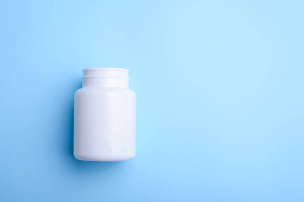 White pill bottle on light blue background. Copy space for text, mock up.