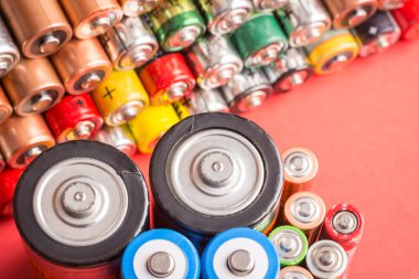 Kırmızı arka planda kullanılmış pil yığını. Güç kavramı