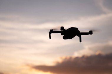 Mavi gökyüzünde süzülen İHA silueti bulutlu bir gökyüzü. Yeni teknolojiler, yükseklikten video ve fotoğraf yapmak.