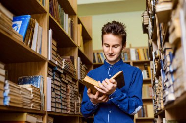 Kütüphanede elinde kitap olan mutlu bir öğrenci. Eğitim kavramı