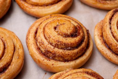 Altın renkli tarçınlı rulo, arka kağıda yakın. Evde pişirme, aromatik pasta, lezzetli çörekler..
