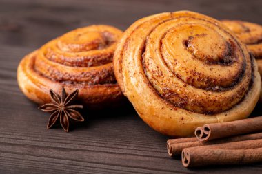 Tarçınlı çörekler koyu ahşap masaya yakın. Anason yıldızı ve tarçın sarmal rulo ve aromatik baharatların yakınına yapışır..