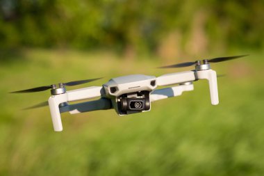 Havada uçan küçük bir dron. Modern insansız hava aracı yandan uçuyor ve video çekiyor