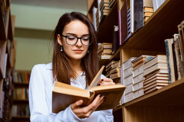 図書館で一人で働く女性学生に集中し プレゼンテーションのための情報を見つけるために多くの本を勉強します 図書館の大学生 — ストック写真