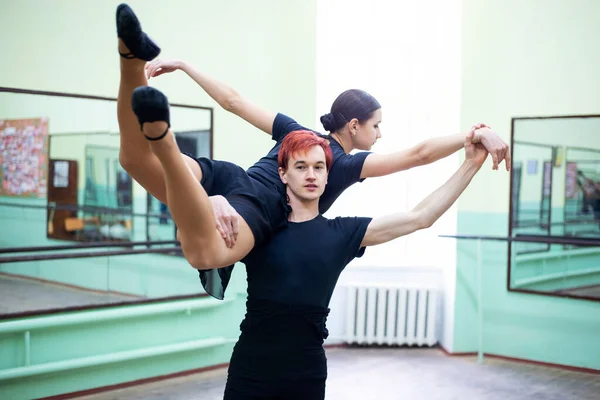 Pair of professional dancers doing difficult trick or gimmick in the dancing studio. Male and female dancers during dance practice