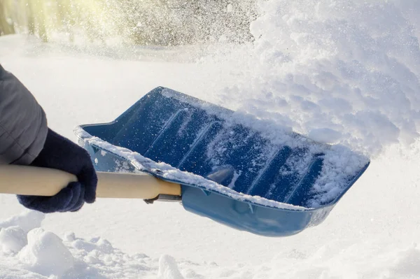 Kışın güneşli bir sabah kar fırtınasından sonra kar temizleyen genç bir adam. Temizlik yaparken kar atmak