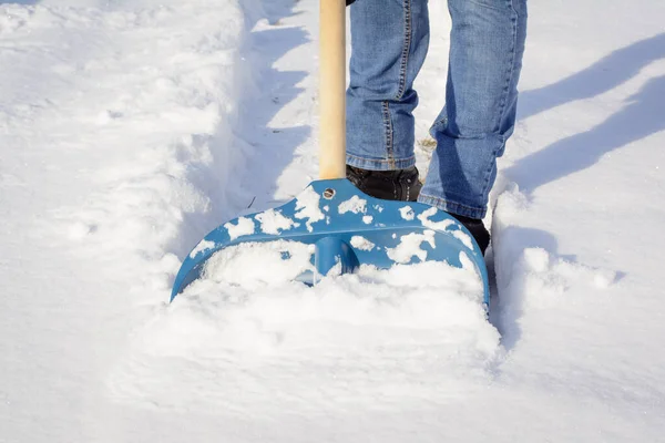 郊外の民家の前で狭い道を掃除している若者 日当たりの良い冬の朝に大雪の後に雪を掘る — ストック写真