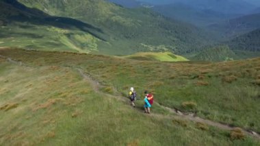 Sırt çantalı iki yürüyüşçü Karpat dağlarında dağ sıraları boyunca yürüyorlar.