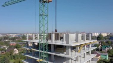 İşçiler, modern binanın büyük inşaat sahasında vinç ve çelik beton takviyesi ile çalışıyorlar. Modern monolitik endüstriyel yapı.