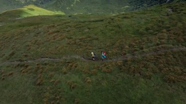 Sırt çantalı iki yürüyüşçü Karpat dağlarında dağ sıraları boyunca yürüyorlar..