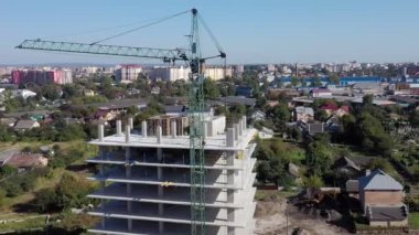 İşçiler, modern binanın büyük inşaat sahasında vinç ve çelik beton takviyesi ile çalışıyorlar. Modern monolitik endüstriyel yapı.