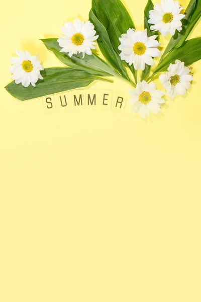 Text SUMMER from letters and field chamomiles flowers on yellow background. Greeting card Flat Lay Copy space Concept Hello summer, summertime.