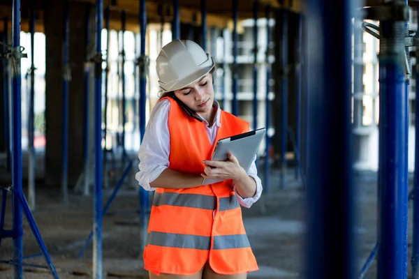 Construction concept of Engineer or Architect working at Construction Site. A woman with a tablet at a construction site. Bureau of Architecture.
