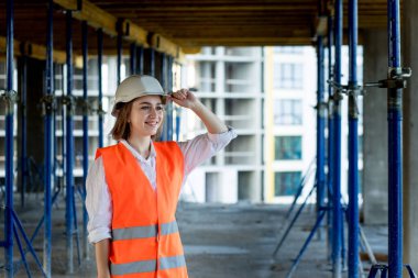 Güzel kadın mimarın portresi boş boş duruyor ve binaların arka planına gülümsüyor..