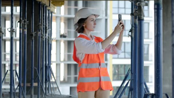 Kvinnlig Byggare Sms Och Knacka Smartphone Och Titta Bort — Stockvideo
