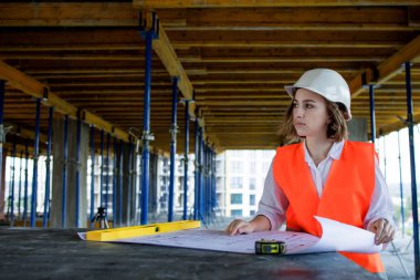 Şablon planıyla inşaat alanının içinde çalışan, gezinen mimar veya mühendis.