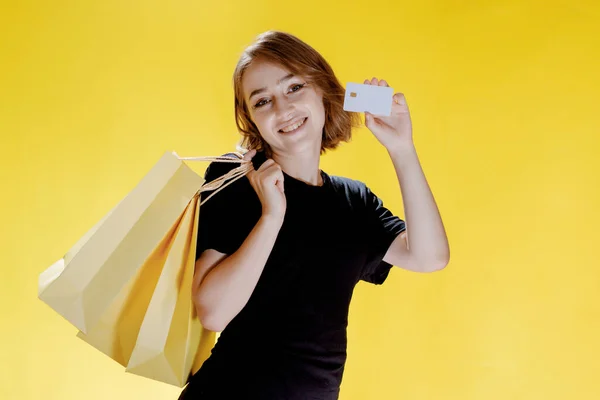 Sarı Arka Planda Paketleri Olan Neşeli Bir Kadın Alışveriş Gezisi — Stok fotoğraf