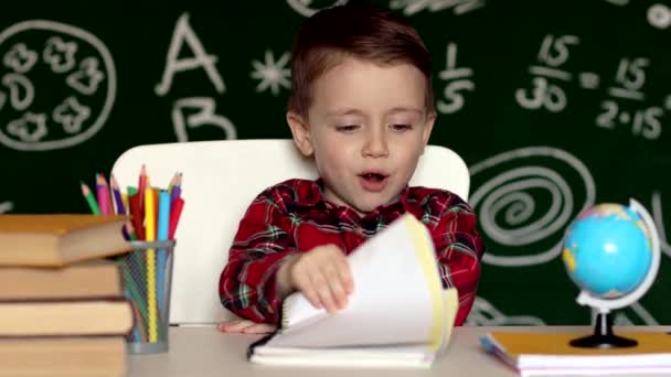 Słodki chłopiec odrabia pracę domową, kolorowanki, pisanie i malowanie. Dzieci malują. Dzieci rysują. Przedszkolak z książkami w domu. Przedszkolaki uczą się pisać i czytać. Kreatywny chłopiec.. — Wideo stockowe