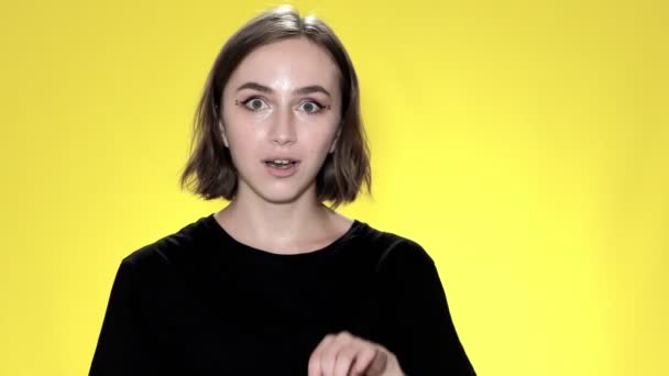 Улыбающаяся молодая женщина держит кредитку на желтом фоне — стоковое видео