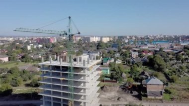 İşçiler, modern binanın büyük inşaat sahasında vinç ve çelik beton takviyesi ile çalışıyorlar. Modern monolitik endüstriyel yapı