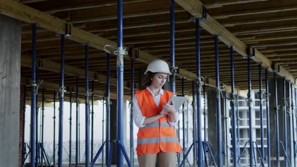 Ingegnere o architetto che lavora in cantiere. Una donna con una tavoletta in un cantiere. Concetto costruzione — Video Stock