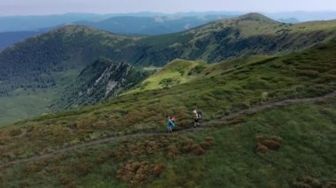 Sırt çantalı iki yürüyüşçü Karpat dağlarında dağ sıraları boyunca yürüyorlar..