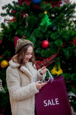 Mutlu kadın, dükkanlarda satıştan sembollü kağıt torbaları tutuyor. Noel 'de, şehrin her yerinde satışları var. Alışveriş kavramı, tatiller, mutluluk, Noel satışları
