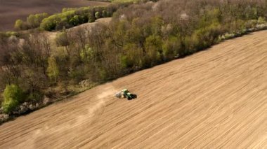Havadan bakıldığında büyük bir traktör kuru bir alan oluşturuyor. Yukarıdan aşağıya traktör, toprağı işliyor ve kuru bir tarla ekiyor. Hava traktörü, tarla ekimi için çayırları kesiyor.