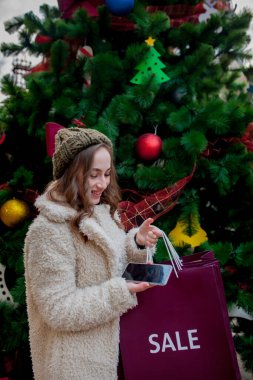 Mutlu kadın, dükkanlarda satıştan sembollü kağıt torbaları tutuyor. Noel 'de, şehrin her yerinde satışları var. Alışveriş kavramı, tatiller, mutluluk, Noel satışları