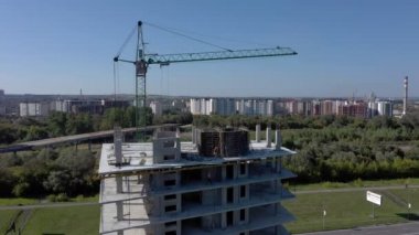 İşçiler, modern binanın büyük inşaat sahasında vinç ve çelik beton takviyesi ile çalışıyorlar. Modern monolitik endüstriyel yapı.