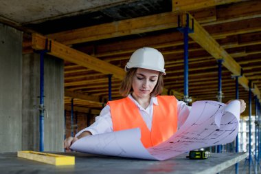 Şablon planıyla inşaat alanının içinde çalışan, gezinen mimar veya mühendis.