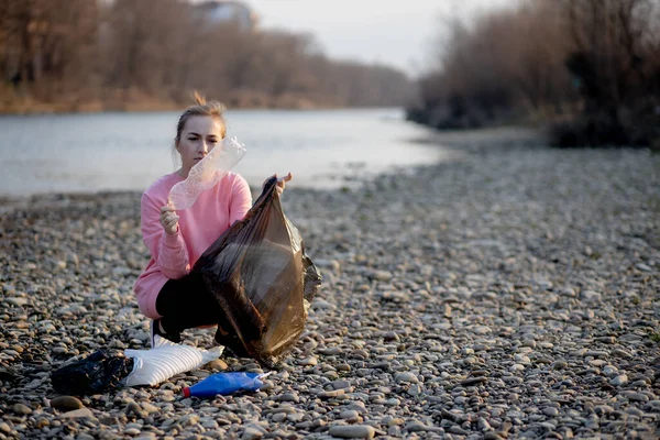 年轻的女志愿者在河里捡垃圾 — 图库照片