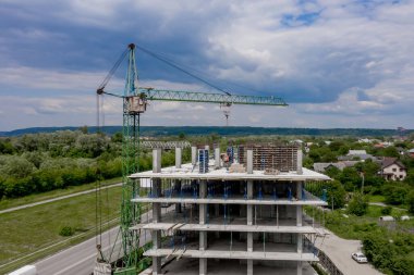 İşçiler, modern binanın büyük inşaat sahasında vinç ve çelik beton takviyesi ile çalışıyorlar. Modern monolitik endüstriyel yapı.