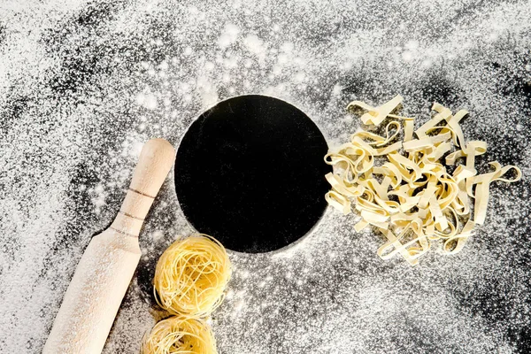 焼きたてのパスタは 小麦粉をまぶした暗い表面に横たわっています イタリアのパスタ タグリアテル 生パスタ イタリアのパスタレシピ トップビュー コピースペース — ストック写真