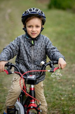 Parkta bisikletli kasklı gülümseyen bir çocuğun portresi..