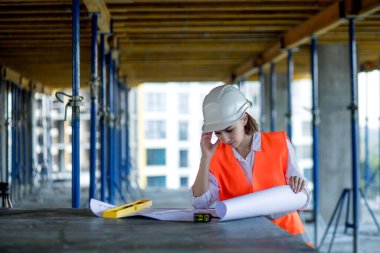 Şablon planıyla inşaat alanının içinde çalışan, gezinen mimar veya mühendis.