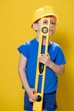 Anaokulu öğrencisi inşaat seviyesini elinde tutuyor. İnşaatçı olma hayalleri kuruyor..