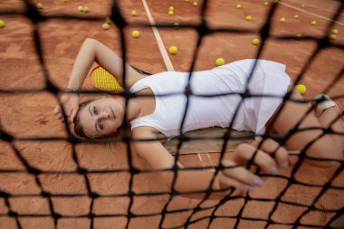Tenis antrenmanından sonra dinleniyorum. Beyaz üniformalı, spor şapkalı, tenis kortunda uzanan genç ve güzel bir kız..