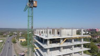 İşçiler, modern binanın büyük inşaat sahasında vinç ve çelik beton takviyesi ile çalışıyorlar. Modern monolitik endüstriyel yapı.