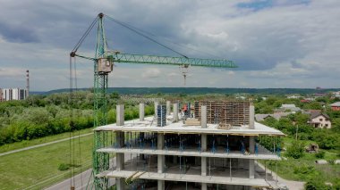 İşçiler, modern binanın büyük inşaat sahasında vinç ve çelik beton takviyesi ile çalışıyorlar. Modern monolitik endüstriyel yapı.