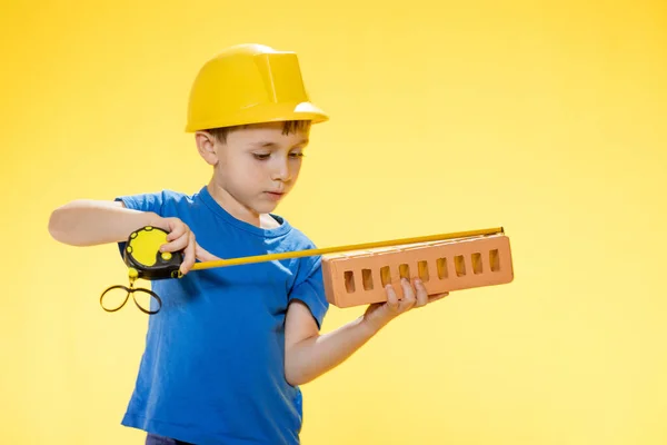 Menino Capacete Construção Segura Tijolo Suas Mãos Mede Com Uma — Fotografia de Stock