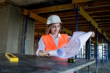 Şablon planıyla inşaat alanının içinde çalışan, gezinen mimar veya mühendis.
