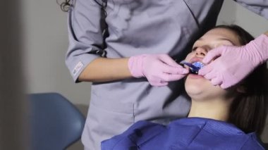 Kadın dişlerinde diş izi tepsisi kullanan ortodontist. Diş implantı için parmak izli diş spatulası..