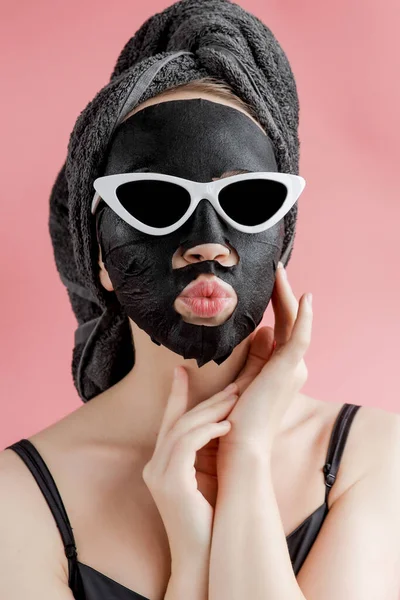 Jovem Mulher Óculos Appling Máscara Facial Tecido Cosmético Preto Fundo — Fotografia de Stock