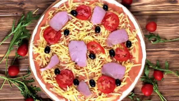 トマト、オリーブ、ハムの生ピザ、古い木製のテーブルのイタリアスタイル、トップビュー. — ストック動画