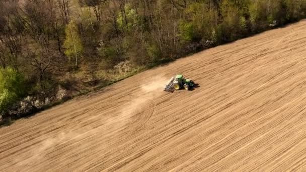 Großer Traktor, der ein trockenes Feld bearbeitet. Von oben nach unten Traktor, der Boden bearbeitet und ein trockenes Feld aussät. Traktor schneidet Furchen im Feld für die Aussaat — Stockvideo